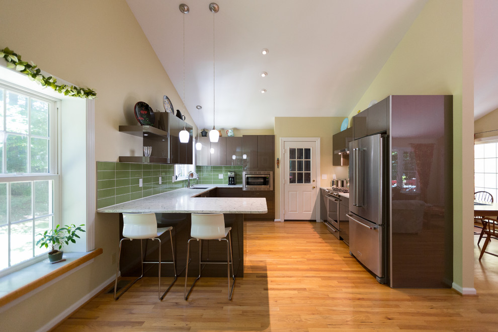 ローリーにある高級な広いモダンスタイルのおしゃれなキッチン (シングルシンク、フラットパネル扉のキャビネット、茶色いキャビネット、クオーツストーンカウンター、緑のキッチンパネル、ガラスタイルのキッチンパネル、シルバーの調理設備、無垢フローリング、黄色い床、マルチカラーのキッチンカウンター) の写真