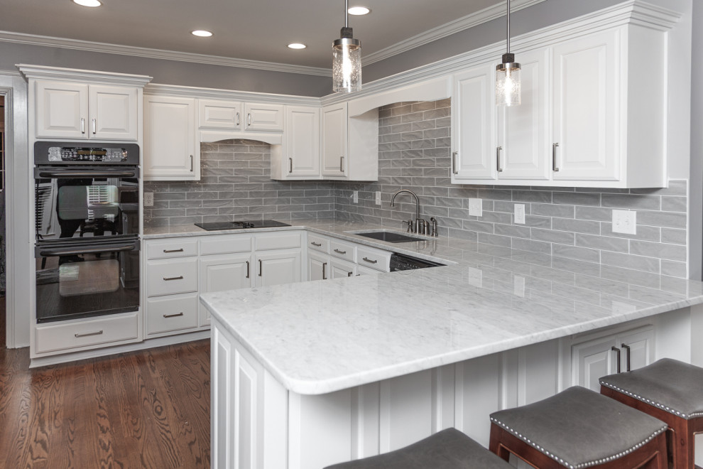 Inredning av ett modernt mellanstort grå grått kök, med en dubbel diskho, luckor med upphöjd panel, vita skåp, marmorbänkskiva, grått stänkskydd, stänkskydd i porslinskakel, rostfria vitvaror, mellanmörkt trägolv och en halv köksö