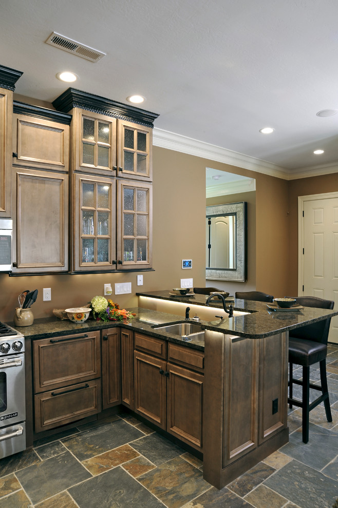 Example of a small classic l-shaped slate floor open concept kitchen design in Cincinnati with beaded inset cabinets, brown cabinets, granite countertops, paneled appliances and a peninsula