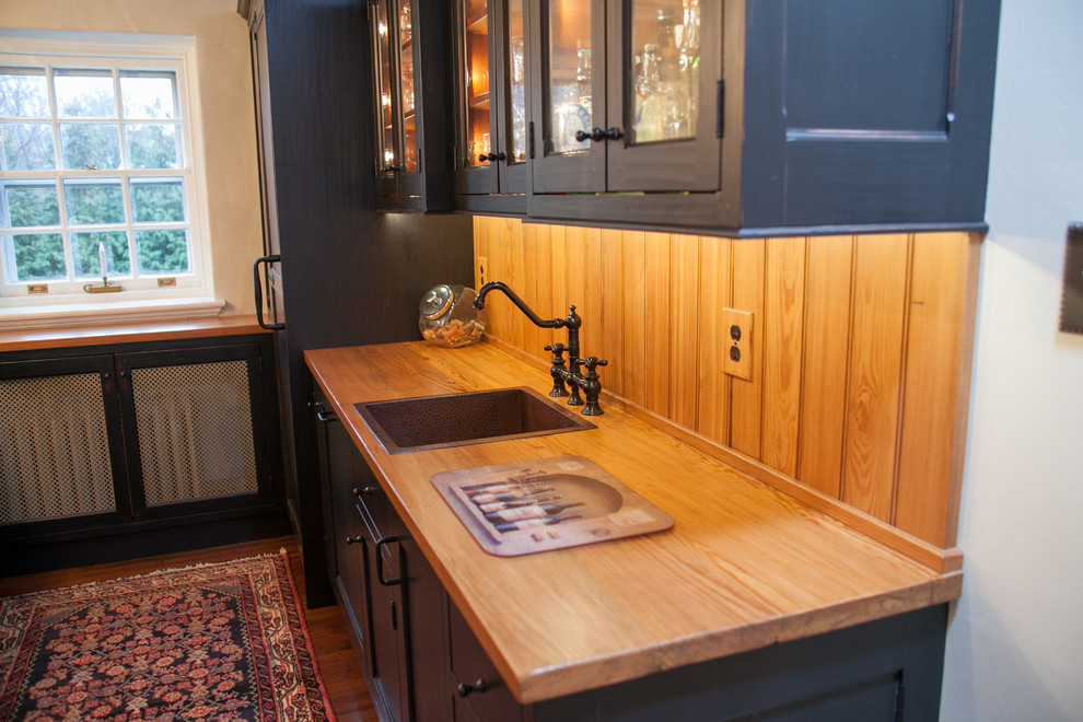 Photo of a medium sized traditional u-shaped enclosed kitchen in Philadelphia with a built-in sink, recessed-panel cabinets, black cabinets, wood worktops, integrated appliances, medium hardwood flooring and a breakfast bar.