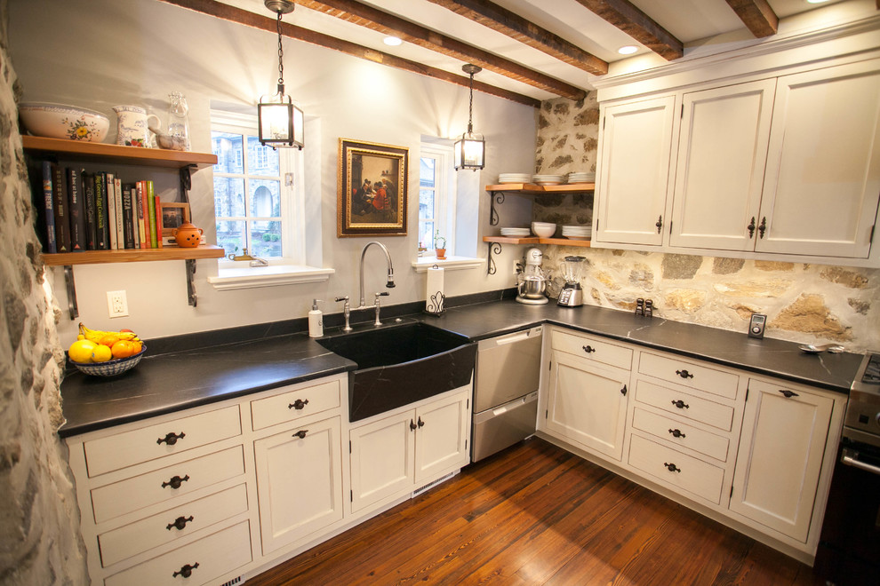 Inredning av ett klassiskt avskilt, mellanstort l-kök, med en rustik diskho, luckor med infälld panel, vita skåp, bänkskiva i täljsten, rostfria vitvaror och mellanmörkt trägolv