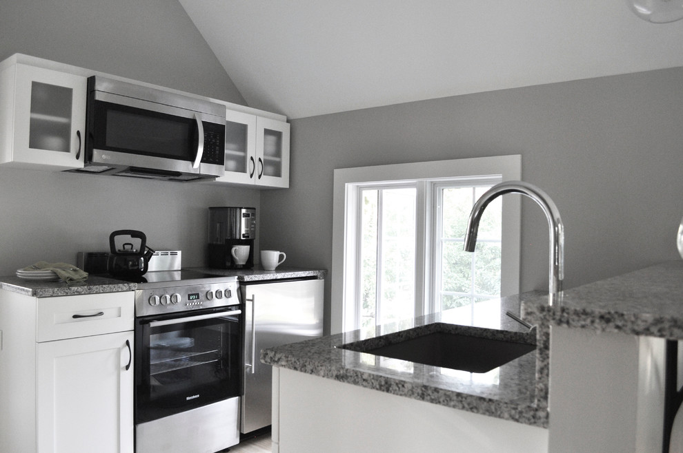 Foto på ett litet funkis kök, med en undermonterad diskho, skåp i shakerstil, vita skåp, granitbänkskiva, rostfria vitvaror och mellanmörkt trägolv