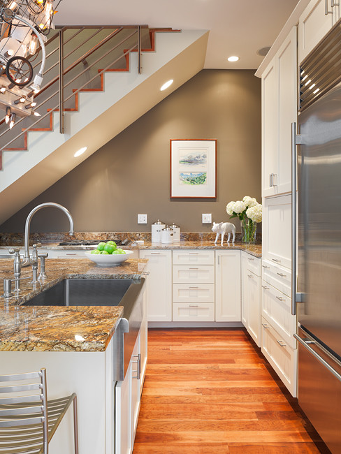 Foto på ett funkis kök, med en rustik diskho, skåp i shakerstil, vita skåp, granitbänkskiva, grönt stänkskydd, stänkskydd i sten, rostfria vitvaror, ljust trägolv och en köksö