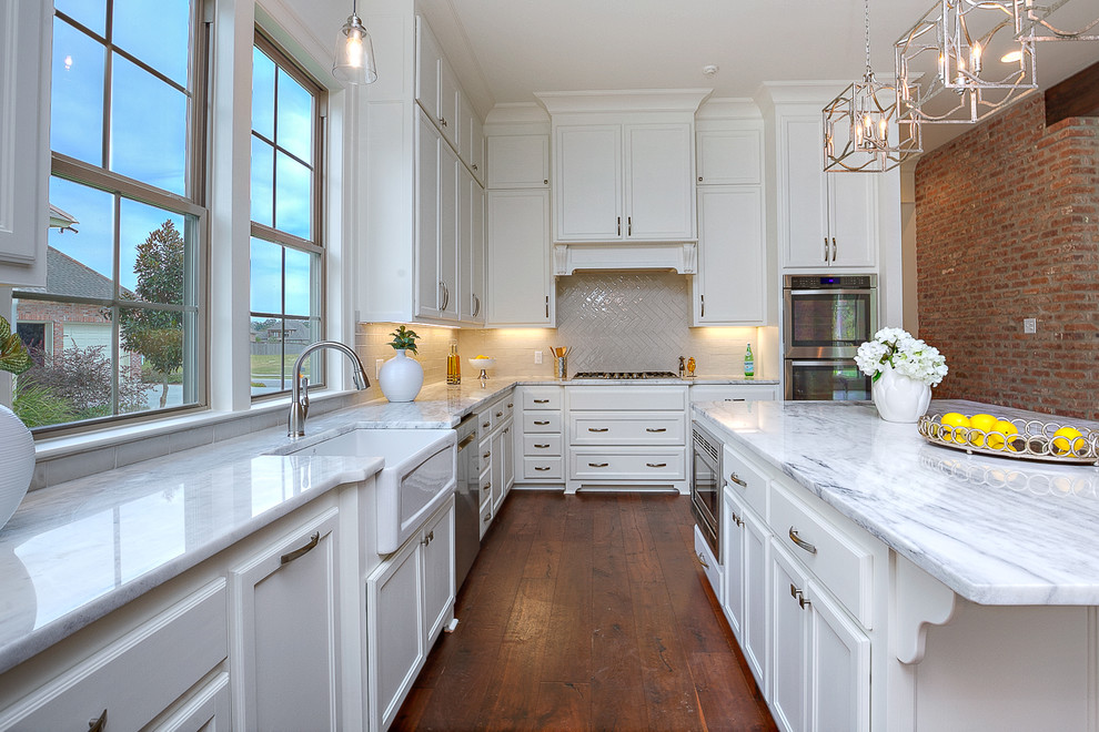 Exempel på ett stort klassiskt vit vitt kök, med en rustik diskho, luckor med upphöjd panel, vita skåp, marmorbänkskiva, grått stänkskydd, stänkskydd i porslinskakel, rostfria vitvaror, mellanmörkt trägolv, en köksö och brunt golv