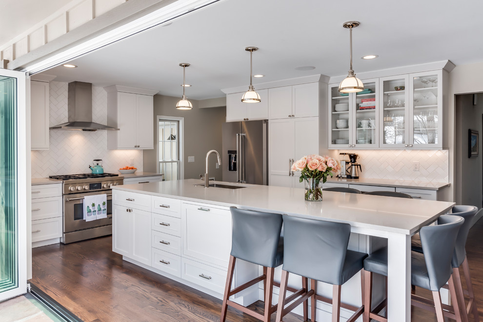 Large classic kitchen/diner in Denver with a submerged sink, shaker cabinets, white cabinets, engineered stone countertops, white splashback, porcelain splashback, stainless steel appliances, dark hardwood flooring, an island and grey worktops.
