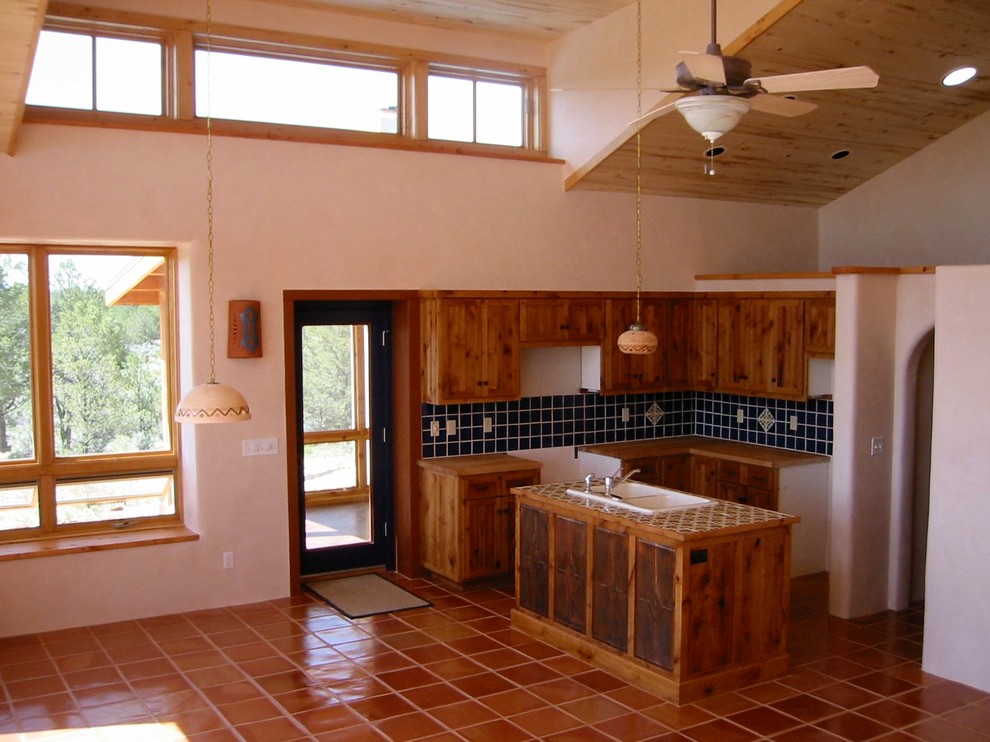Immagine di una cucina eclettica di medie dimensioni con lavello a doppia vasca, ante con bugna sagomata, ante in legno scuro, top in legno, paraspruzzi blu, paraspruzzi con piastrelle in ceramica e pavimento in terracotta