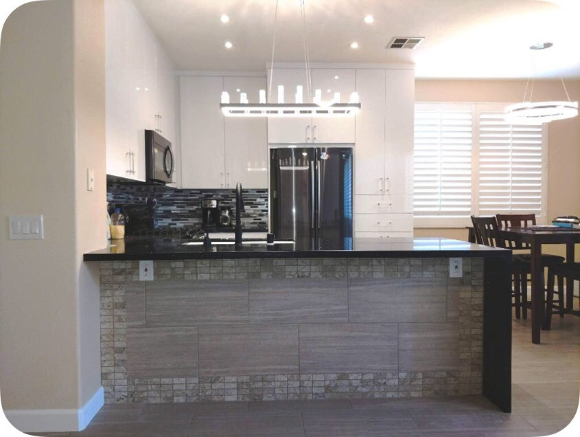 Idéer för att renovera ett litet funkis svart svart kök, med en undermonterad diskho, släta luckor, vita skåp, bänkskiva i kvarts, flerfärgad stänkskydd, stänkskydd i stickkakel, svarta vitvaror, laminatgolv, en halv köksö och beiget golv