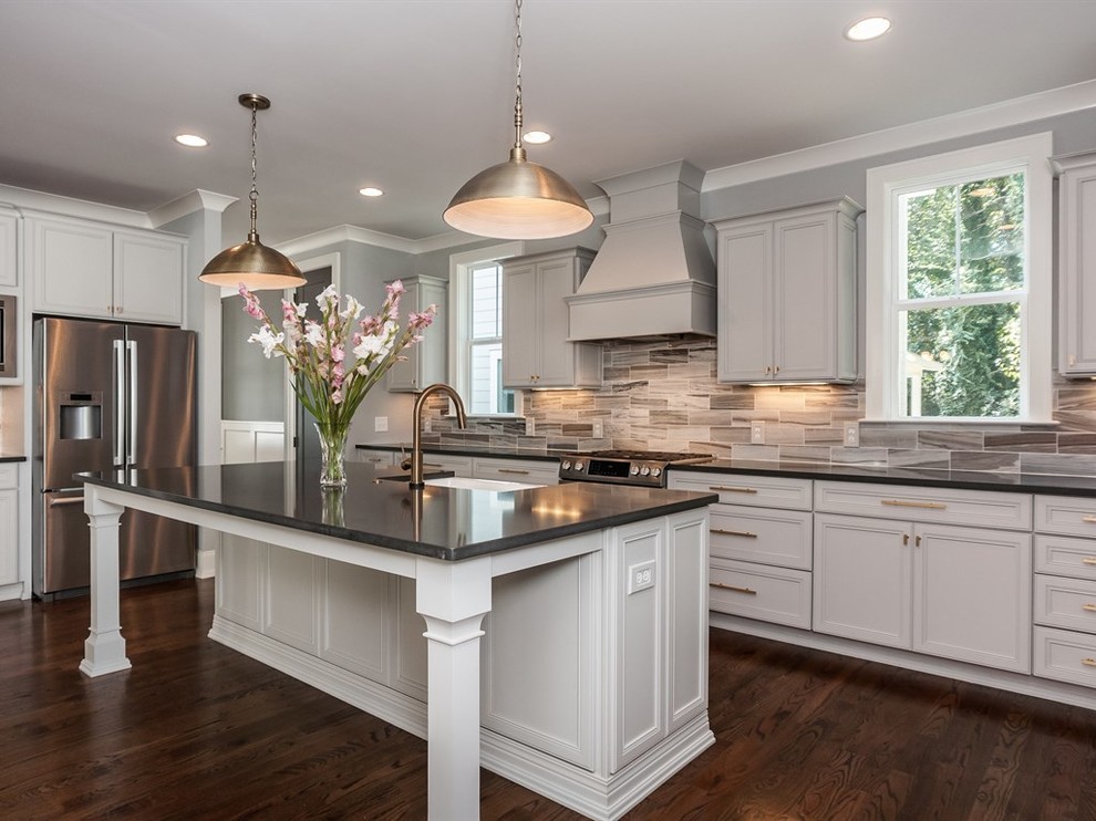 Large transitional l-shaped medium tone wood floor open concept kitchen photo in Raleigh with a farmhouse sink, recessed-panel cabinets, gray cabinets, quartz countertops, gray backsplash, stone tile backsplash, stainless steel appliances and an island