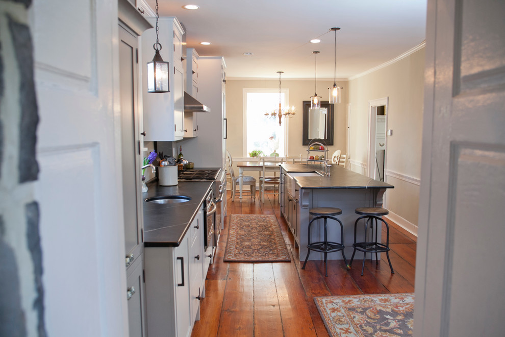 Eat-in kitchen - large cottage galley medium tone wood floor eat-in kitchen idea in Philadelphia with a farmhouse sink, shaker cabinets, gray cabinets, soapstone countertops, stainless steel appliances and an island