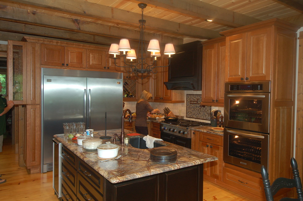 Foto di una cucina classica con lavello sottopiano, ante con bugna sagomata, ante in legno scuro, top in granito, paraspruzzi beige e elettrodomestici in acciaio inossidabile