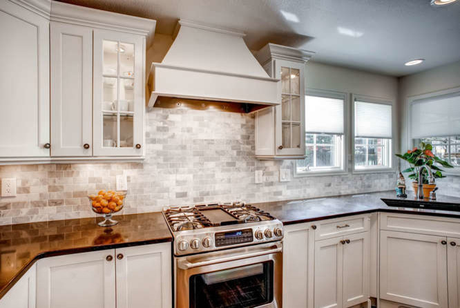 Exempel på ett mellanstort klassiskt kök, med en undermonterad diskho, vita skåp, bänkskiva i kvarts, rostfria vitvaror, mellanmörkt trägolv, en köksö, skåp i shakerstil, grått stänkskydd och stänkskydd i stenkakel