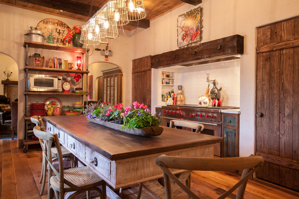 Farmhouse galley eat-in kitchen photo in Dallas with raised-panel cabinets, stainless steel appliances, a farmhouse sink, distressed cabinets, white backsplash and subway tile backsplash