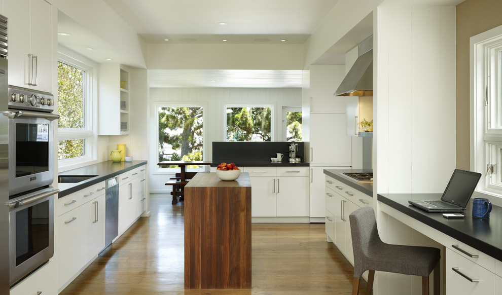Transitional enclosed kitchen photo in San Francisco with stainless steel appliances, granite countertops, an undermount sink, flat-panel cabinets and white cabinets
