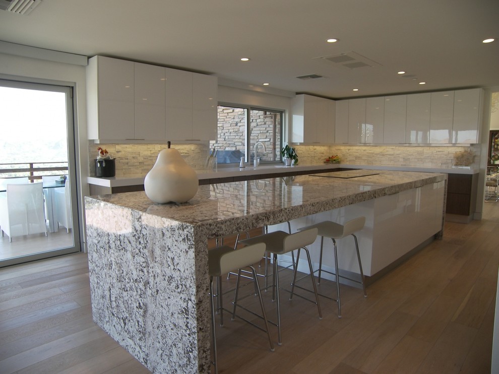 Example of a large trendy u-shaped light wood floor eat-in kitchen design in Phoenix with an integrated sink, flat-panel cabinets, white cabinets, quartzite countertops, white backsplash, stone tile backsplash, paneled appliances and an island