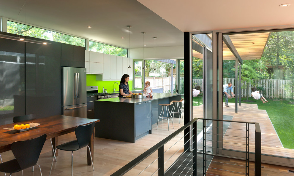 Идея дизайна: прямая кухня в стиле модернизм с обеденным столом, плоскими фасадами, серыми фасадами, зеленым фартуком и техникой из нержавеющей стали