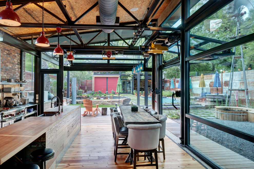 Urban kitchen/diner in Dallas with a belfast sink, open cabinets, stainless steel cabinets, wood worktops, brick splashback, stainless steel appliances, medium hardwood flooring and an island.