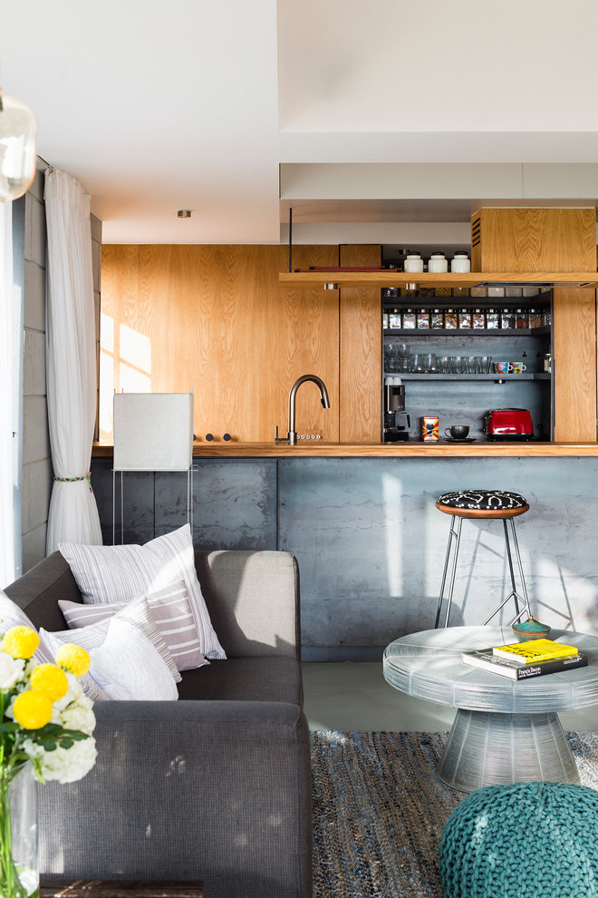 Small trendy single-wall concrete floor eat-in kitchen photo in Pune with flat-panel cabinets, an undermount sink, light wood cabinets, stainless steel countertops, metallic backsplash, stainless steel appliances and an island