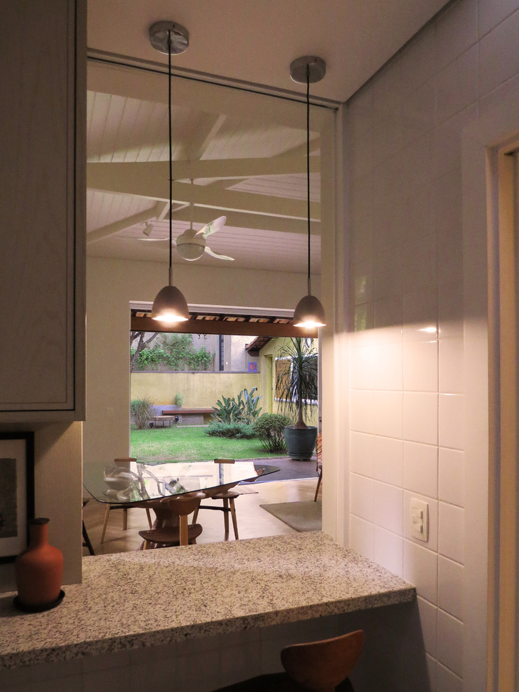Cette photo montre une cuisine chic avec un placard à porte affleurante, des portes de placard grises, un plan de travail en granite, une crédence blanche et une crédence en céramique.