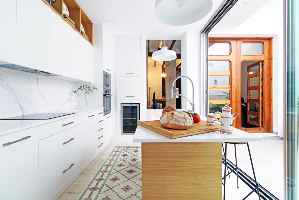 Exemple d'une cuisine ouverte méditerranéenne en L de taille moyenne avec un placard à porte plane, des portes de placard blanches, un sol en carrelage de céramique, îlot, un sol vert et un plan de travail blanc.