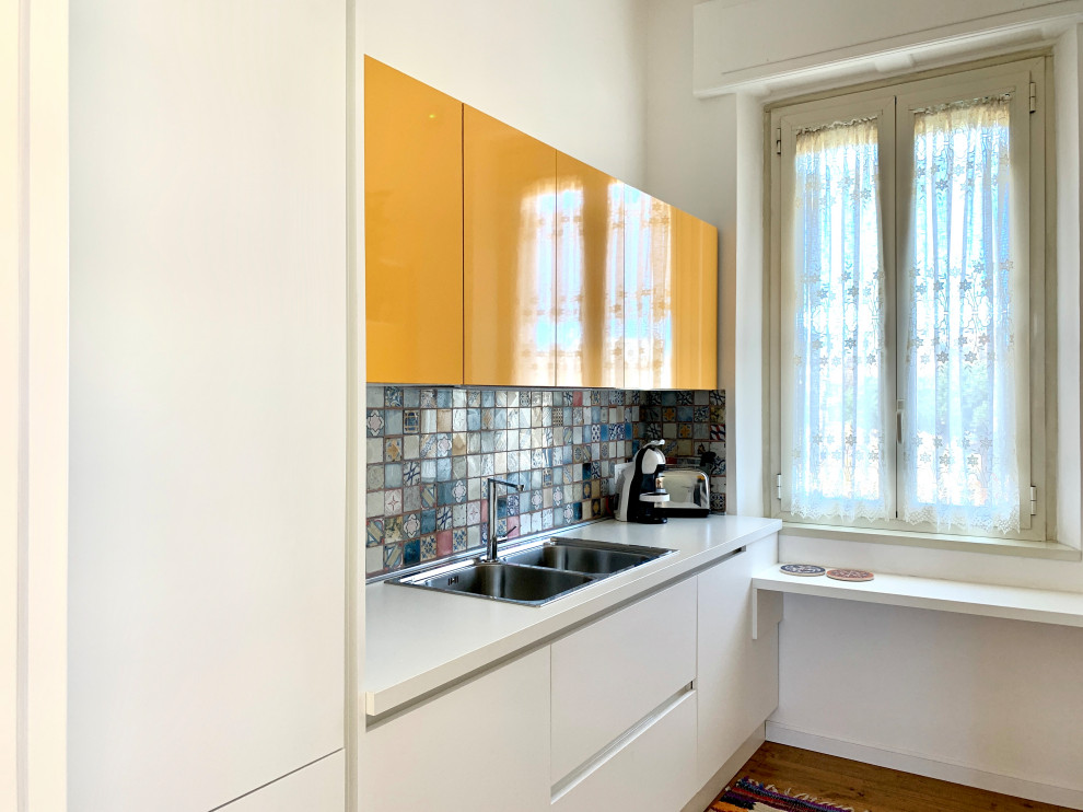 Ispirazione per una piccola cucina con lavello a doppia vasca, ante gialle, paraspruzzi con piastrelle di cemento, pavimento in legno massello medio e top bianco
