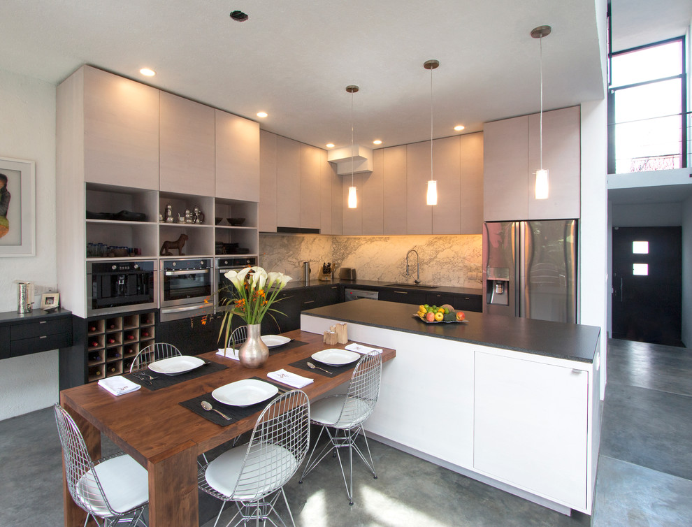 Foto di una cucina minimalista di medie dimensioni con lavello sottopiano, ante lisce, ante nere, top in granito, paraspruzzi beige, paraspruzzi in lastra di pietra, elettrodomestici in acciaio inossidabile e pavimento in cemento