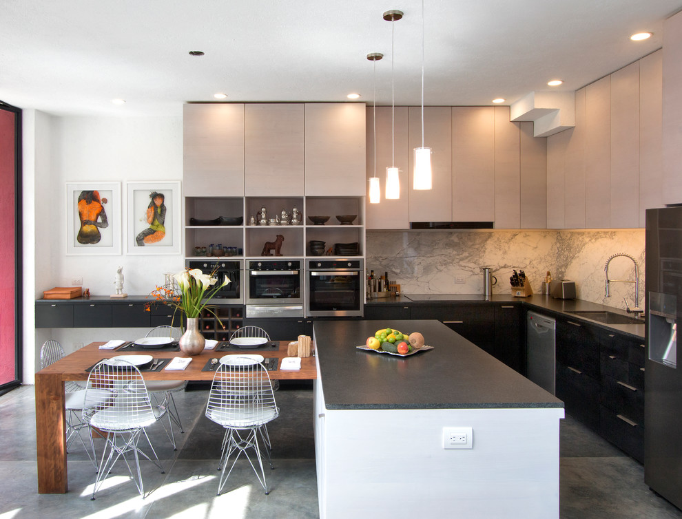 Foto di una cucina moderna di medie dimensioni con lavello sottopiano, ante lisce, ante nere, top in granito, paraspruzzi beige, paraspruzzi in lastra di pietra, elettrodomestici in acciaio inossidabile e pavimento in cemento
