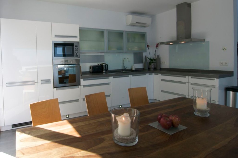 Foto de cocina contemporánea de tamaño medio sin isla con armarios con paneles lisos, puertas de armario blancas y salpicadero blanco