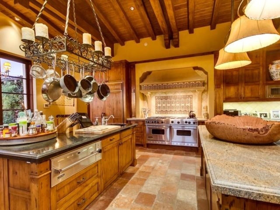 Inspiration for a large mediterranean single-wall travertine floor and multicolored floor enclosed kitchen remodel in San Diego with an undermount sink, recessed-panel cabinets, medium tone wood cabinets, granite countertops, beige backsplash, ceramic backsplash, paneled appliances, two islands and gray countertops