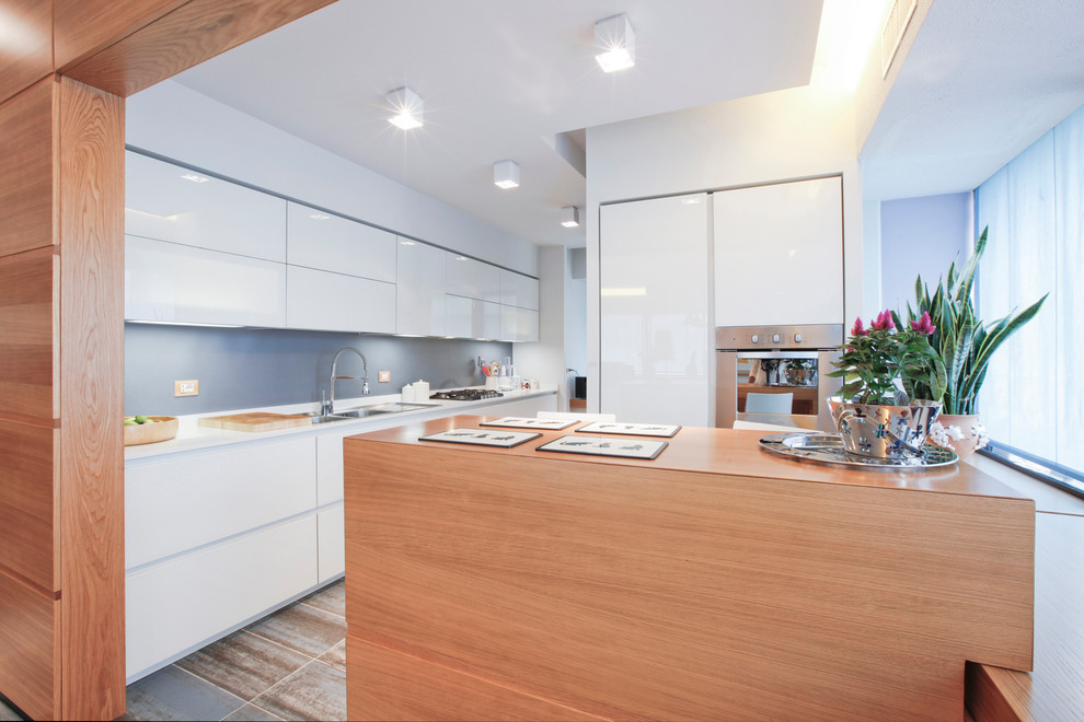 Esempio di una grande cucina abitabile minimal con lavello da incasso, ante lisce, ante bianche e elettrodomestici in acciaio inossidabile