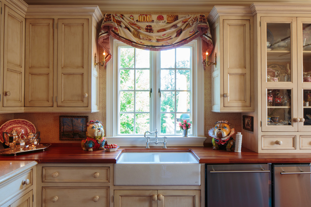 Example of a tuscan kitchen design in Other with a farmhouse sink, recessed-panel cabinets, beige cabinets, wood countertops and stainless steel appliances