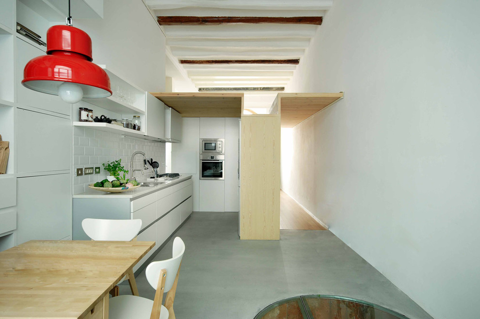 На фото: п-образная кухня-гостиная среднего размера в современном стиле с одинарной мойкой, плоскими фасадами, белыми фасадами и техникой из нержавеющей стали без острова
