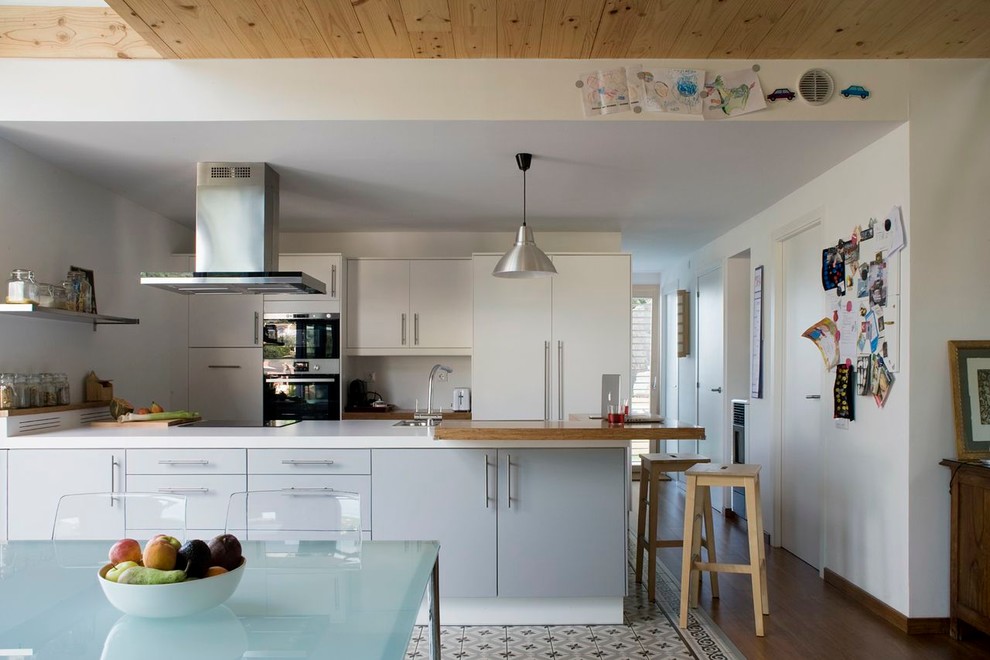 Idéer för ett mellanstort modernt kök, med släta luckor, vita skåp, bänkskiva i koppar, vitt stänkskydd, rostfria vitvaror, klinkergolv i keramik och en halv köksö