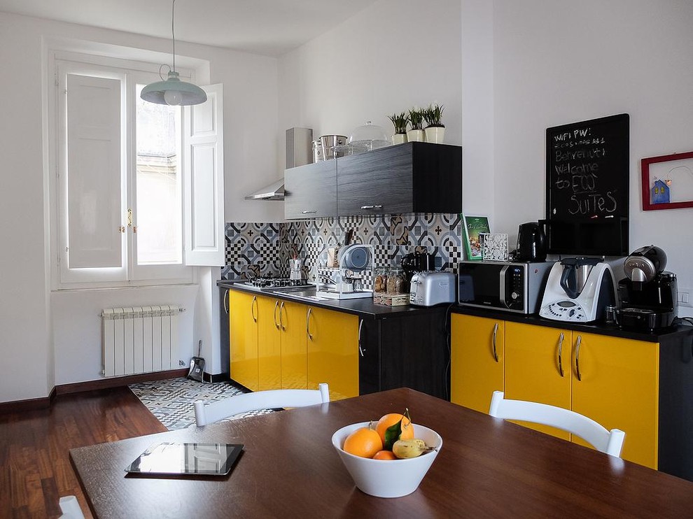 Ejemplo de cocina comedor lineal contemporánea de tamaño medio con fregadero encastrado, armarios con paneles lisos, puertas de armario amarillas, suelo de madera oscura y salpicadero de azulejos de porcelana