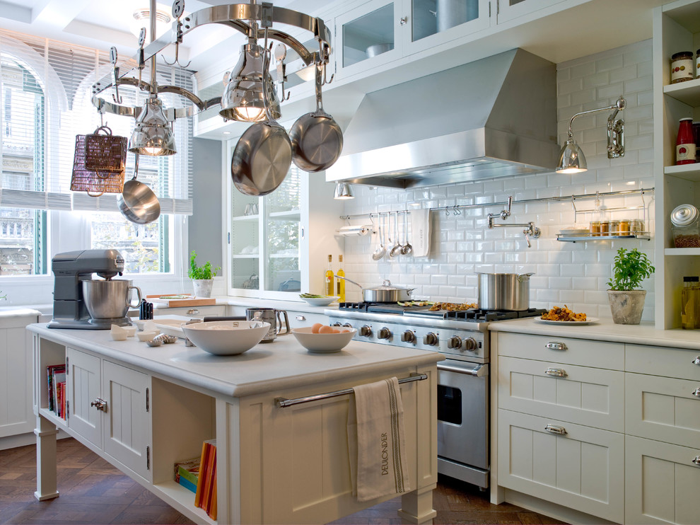 Example of a large urban galley medium tone wood floor enclosed kitchen design in Barcelona with white backsplash, an island, open cabinets, white cabinets, solid surface countertops, subway tile backsplash and stainless steel appliances
