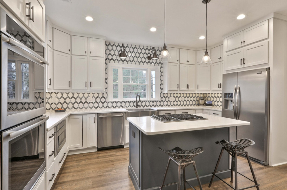 Inspiration for a mid-sized cottage u-shaped vinyl floor and brown floor kitchen remodel in Atlanta with a farmhouse sink, shaker cabinets, white cabinets, quartz countertops, multicolored backsplash, ceramic backsplash, stainless steel appliances, an island and white countertops