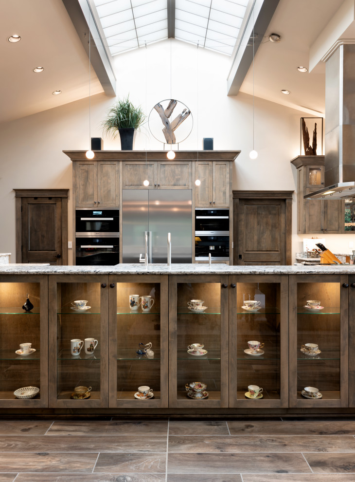 This is an example of an expansive classic u-shaped open plan kitchen in Seattle with a single-bowl sink, shaker cabinets, dark wood cabinets, engineered stone countertops, stainless steel appliances, ceramic flooring, multiple islands, brown floors and multicoloured worktops.