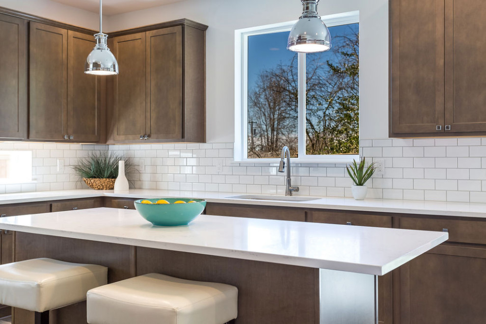 This is an example of a large modern l-shaped open plan kitchen in Seattle with a submerged sink, shaker cabinets, brown cabinets, quartz worktops, white splashback, ceramic splashback, stainless steel appliances, medium hardwood flooring, an island, brown floors and white worktops.