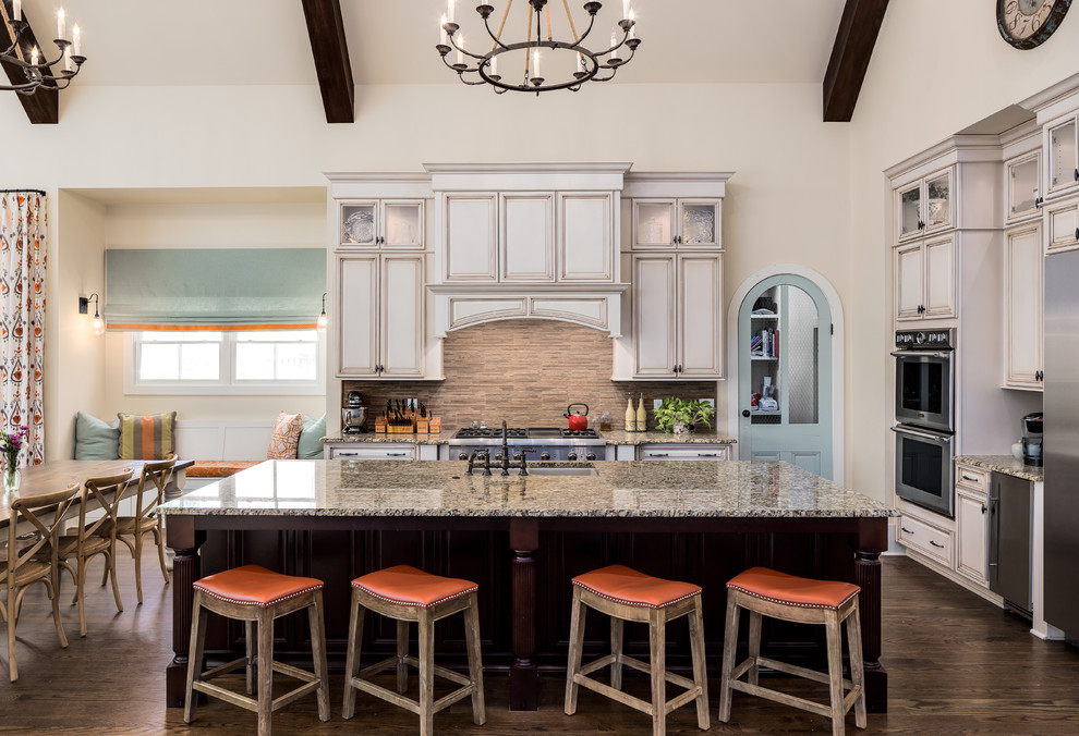 Eat-in kitchen - mid-sized traditional l-shaped dark wood floor eat-in kitchen idea in Nashville with raised-panel cabinets, beige cabinets, beige backsplash, stainless steel appliances, an island, a double-bowl sink, granite countertops and stone tile backsplash