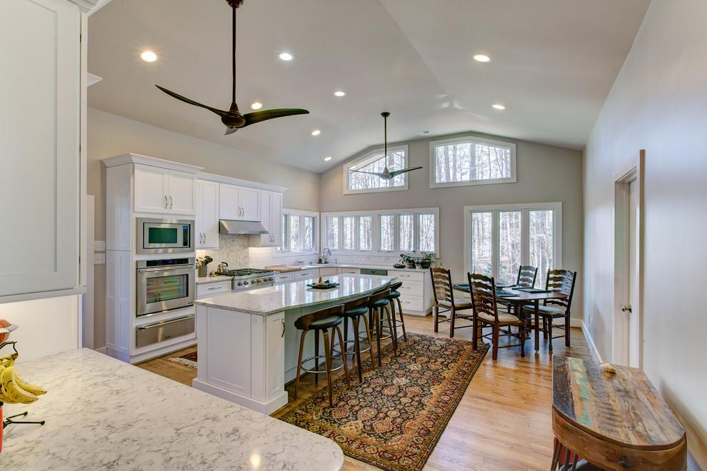 Example of a large transitional u-shaped medium tone wood floor eat-in kitchen design in Raleigh with a single-bowl sink, shaker cabinets, white cabinets, quartz countertops, white backsplash, ceramic backsplash, stainless steel appliances and an island