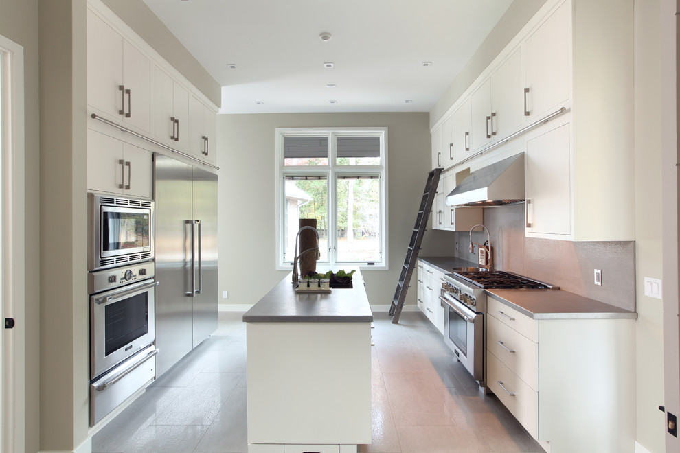 Ejemplo de cocinas en L actual abierta con armarios estilo shaker, puertas de armario blancas, encimera de cemento, suelo de madera en tonos medios y una isla