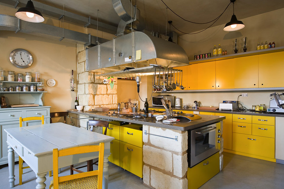 Idéer för att renovera ett industriellt kök och matrum, med släta luckor, gula skåp, rostfria vitvaror, betonggolv och en halv köksö