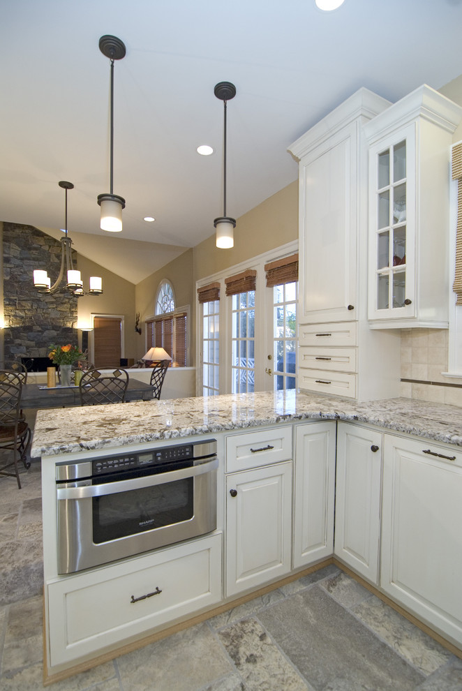 Idées déco pour une cuisine ouverte classique avec un placard avec porte à panneau surélevé, un plan de travail en granite, des portes de placard blanches, une crédence beige et un électroménager en acier inoxydable.