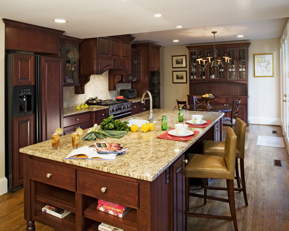 Foto di una cucina parallela tradizionale con top in granito, lavello sottopiano, ante in legno bruno, paraspruzzi beige e paraspruzzi in travertino