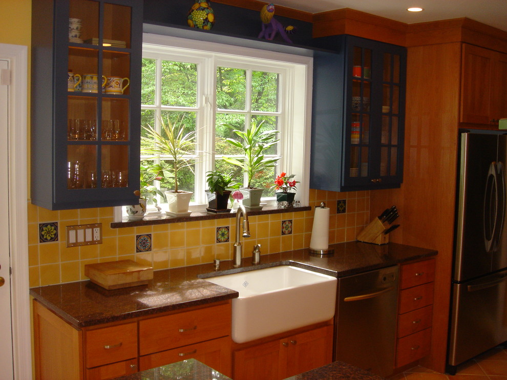 Ejemplo de cocina clásica con encimera de granito, fregadero sobremueble, armarios tipo vitrina, puertas de armario azules, salpicadero amarillo y electrodomésticos de acero inoxidable