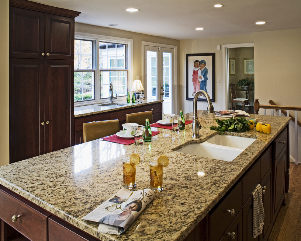 Example of a classic kitchen design in DC Metro with a double-bowl sink, granite countertops, raised-panel cabinets and dark wood cabinets