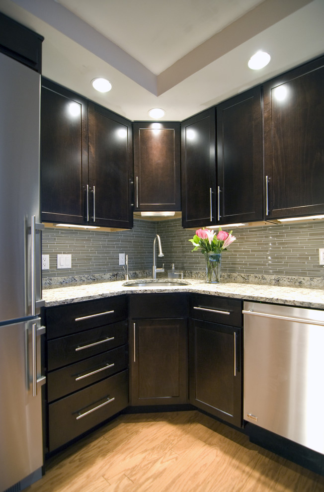 Example of a trendy kitchen design in DC Metro with stainless steel appliances, granite countertops, an undermount sink, recessed-panel cabinets, dark wood cabinets and green backsplash