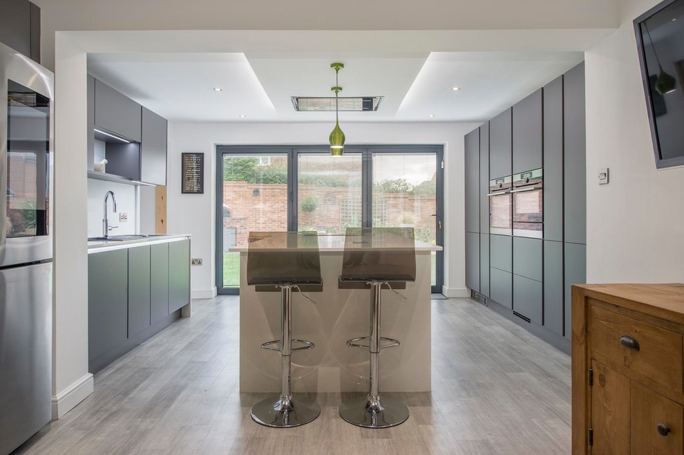 Inspiration for a medium sized contemporary galley kitchen/diner in Other with a built-in sink, flat-panel cabinets, grey cabinets, quartz worktops, stainless steel appliances, laminate floors, an island, multi-coloured floors and white worktops.