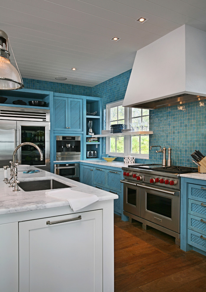 Aménagement d'une cuisine contemporaine avec plan de travail en marbre, un électroménager en acier inoxydable, un placard avec porte à panneau encastré et des portes de placard bleues.
