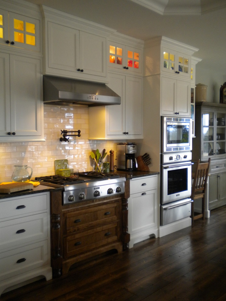 Example of a mid-sized cottage u-shaped dark wood floor open concept kitchen design in Other with a farmhouse sink, shaker cabinets, white cabinets, granite countertops, multicolored backsplash, porcelain backsplash, stainless steel appliances and an island