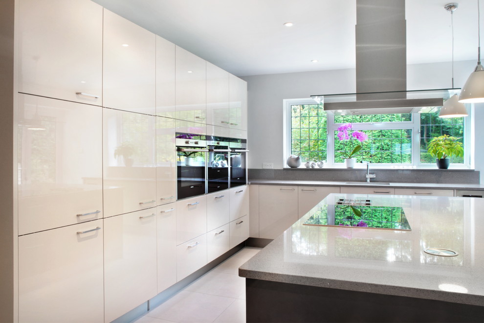 Inspiration for a large contemporary l-shaped kitchen/diner in Hertfordshire with glass-front cabinets, white cabinets, quartz worktops, stainless steel appliances, porcelain flooring, an island and a submerged sink.